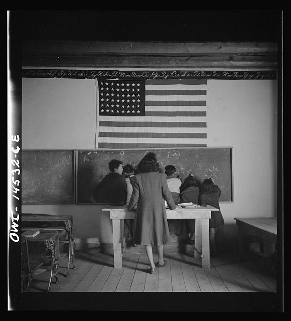 In this isolated mountainous Spanish American community in Ojo Sarco, New Mexico, a one-room school serves students across eight grades with just two teachers. These teachers work with minimal equipment, relying on the blackboard to teach the alphabet, penmanship, and grammar.